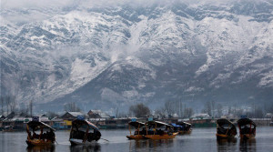 Srinagar: Tourists enjoy Shikara rides at Dal Lake in Srinagar on Friday as snow covered Zabarwan mountains are seen in the background after the season's first snowfall. PTI Photo  (PTI12_11_2015_000124B)